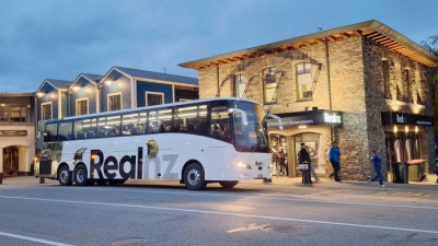 リアルNZのミルフォードサウンドツアーバス、クイーンズタウンビジターセンターにて